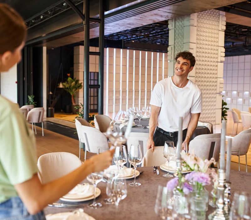 smiling-man-near-festive-tables-looking-at-woman-on-blurred-foreground-banquet-organizers-at-work.jpg